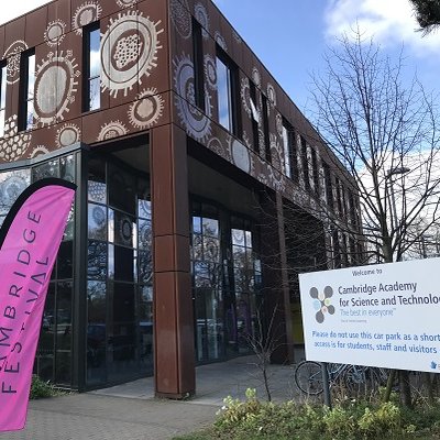 The front of a building with science symbols all over it and a pink flag that reads Cambridge Festival