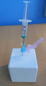 Syringe with needle placed into white block