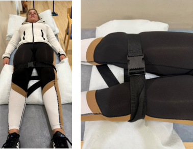 Demonstrating static muscle activation against belt in lying position with pillow under knees and belt around top of knees.