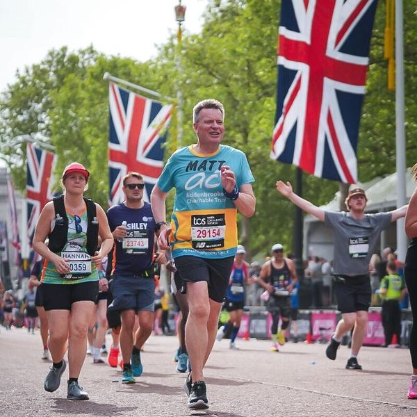 A man running with other people with photos of the Union Jack