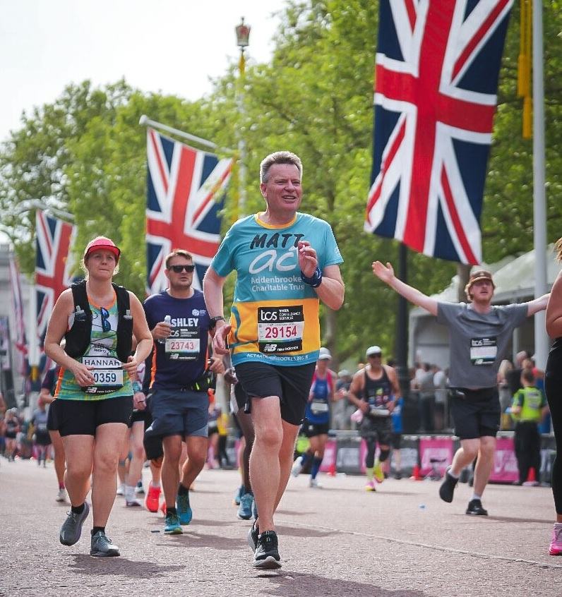A man running with other people with photos of the Union Jack