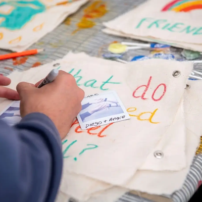 A person's hands drawing and writing during a workshop at the CUH Arts festival