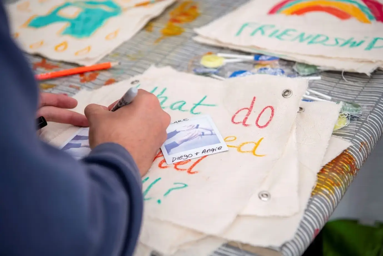 A person's hands drawing and writing during a workshop at the CUH Arts festival