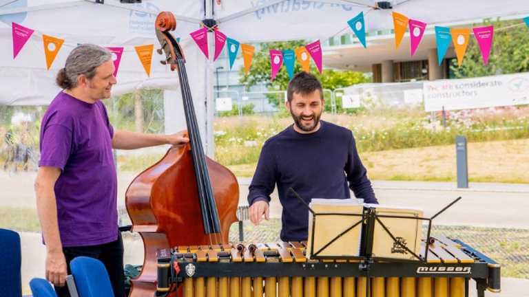 Two musicians play outside for a staff arts festival.