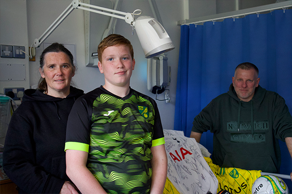 A boy standing next to his mum and dad in hospital