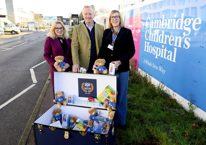 Two women and a man outside Cambridge Children's Hospital, overlooking a chest with teddy bears inside