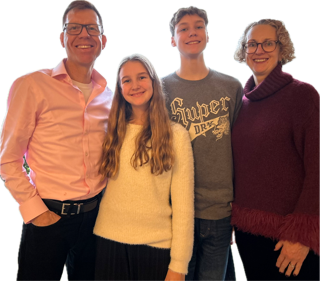 A family photo showing a man with short fair hair and glasses, a girl with long brown hair, a teenage boy, and a woman with curly hair. they are all smiling