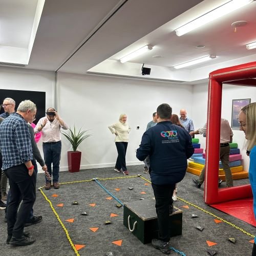 A group of women and men standing around a floor with markings