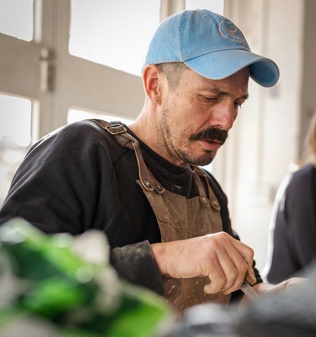 A man wearing a blue hat and an apron painting
