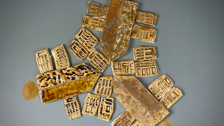 A selection of brown ceramic tiles, handmade with patterns on.