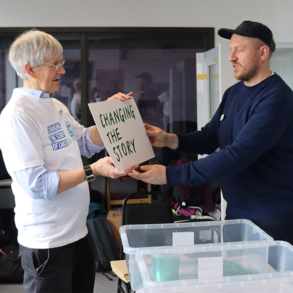 Two men holding a card that says 'Changing The Story'