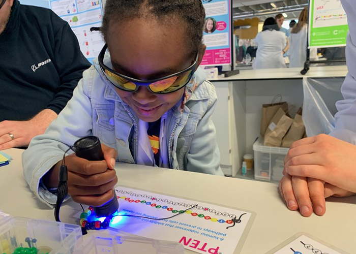 A child wearing sunglasses making a DNA bracelet