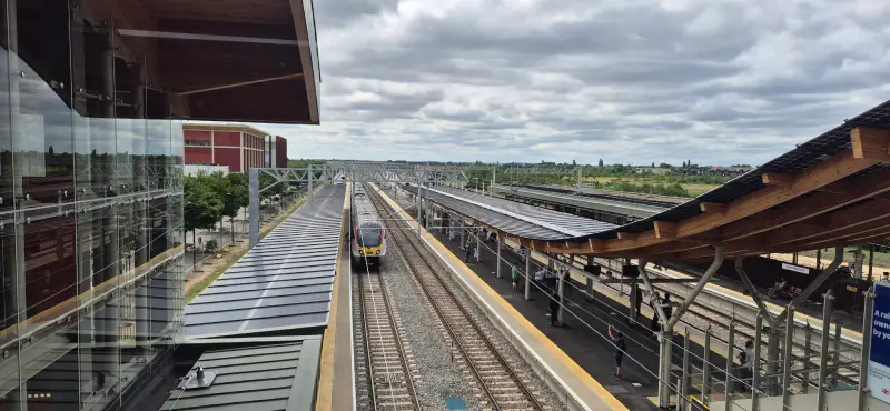 A view South from the Cambridge South footbridge showing the four platforms and a Greater Anglia train