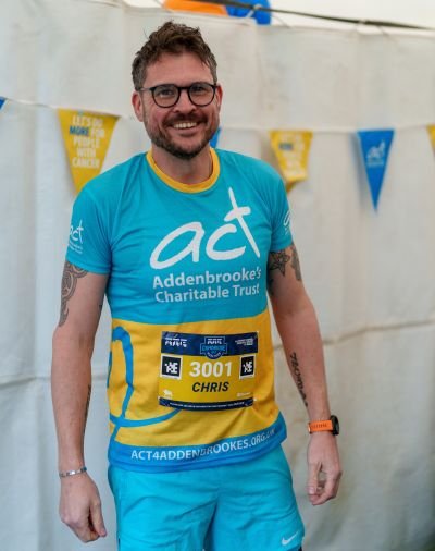 A man wearing a blue ACT t-shirt smiling