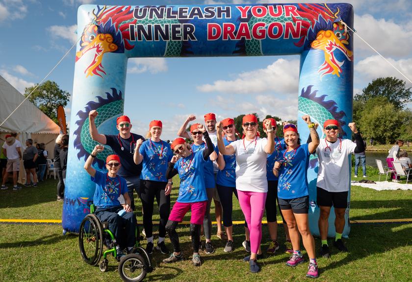 The Cambridge Cancer Research Hospital's dragon boat rowing team are pictured standing under the colourful festival arch