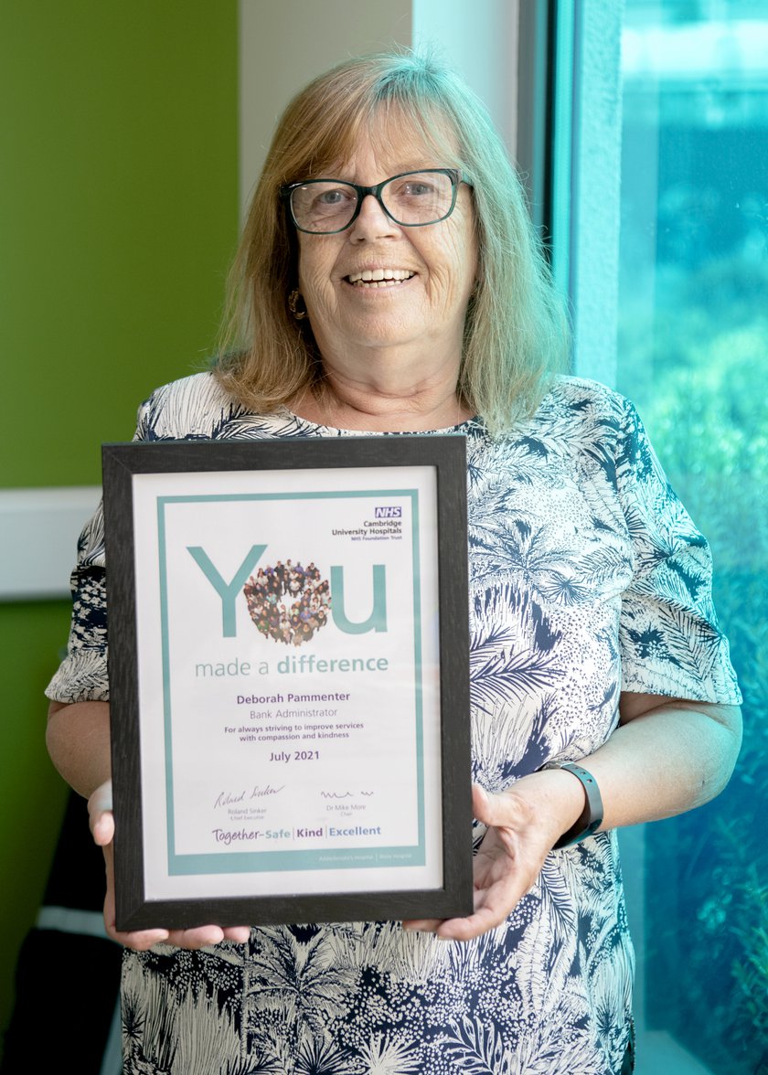 Deborah is smiling and holding her You Made a Difference certificate