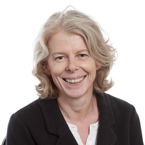 Sue, smiling towards the camera in a professional headshot.