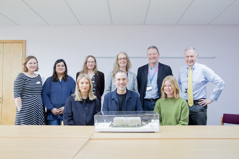 A group of people standing around a model of a hospital