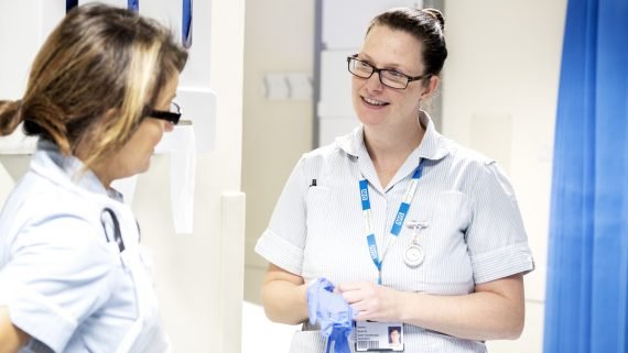 Healthcare support worker talking to colleague during a handover.