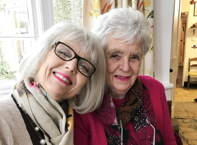 Two well dressed women sitting together and smiling at the camera