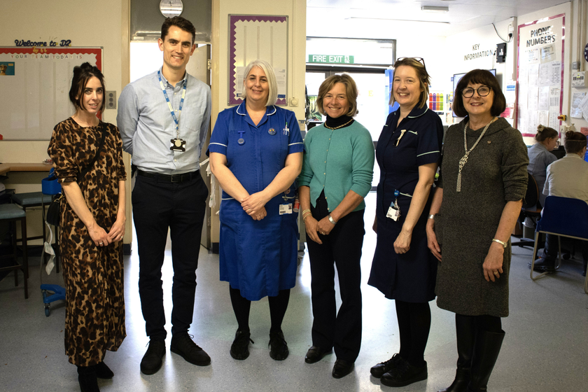 A group of people standing on a hospital ward with a nurse