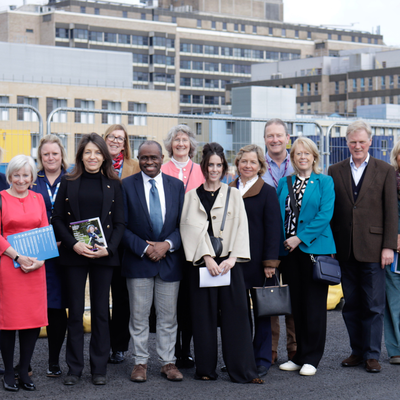 A group of people standing outside the Cambridge Children's Hospital site on a sunny day.