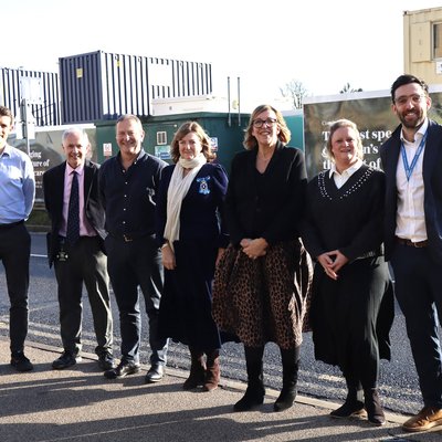 A group of women and men standing in front of Cambridge Children's Hospital hoardings