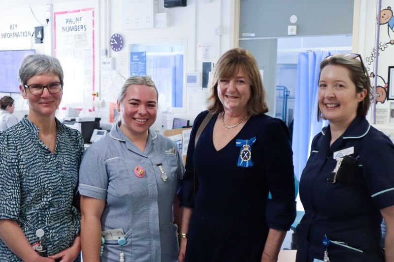 A group of nurses and a psychologist standing next to a woman wearing a medal