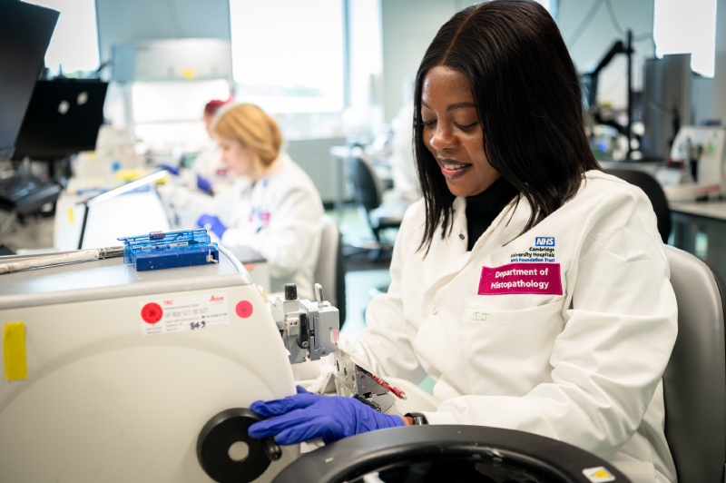 A member of the histopathology team sat at a device used to cut fine slices from tissue samples so they can be studied under a microscope.