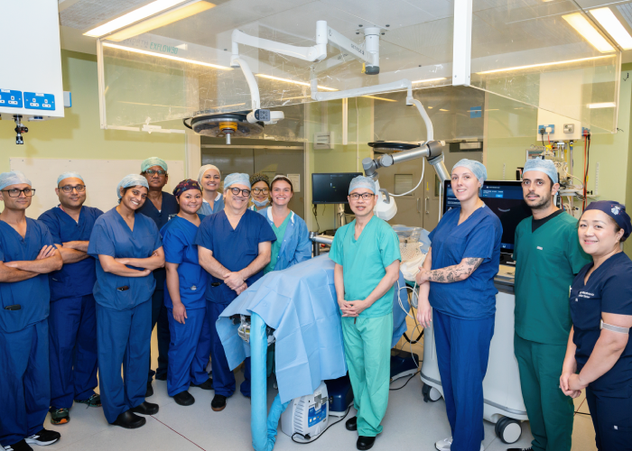 A group of female and male clinical staff smiling around the histotripsy machine in a hospital theatre