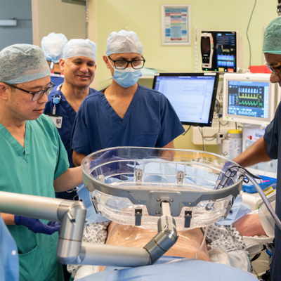 Doctors gathering around a water bath that is positioned above the patient's abdomen