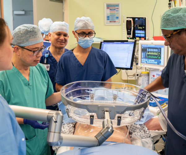 Doctors gathering around a water bath that is positioned above the patient's abdomen