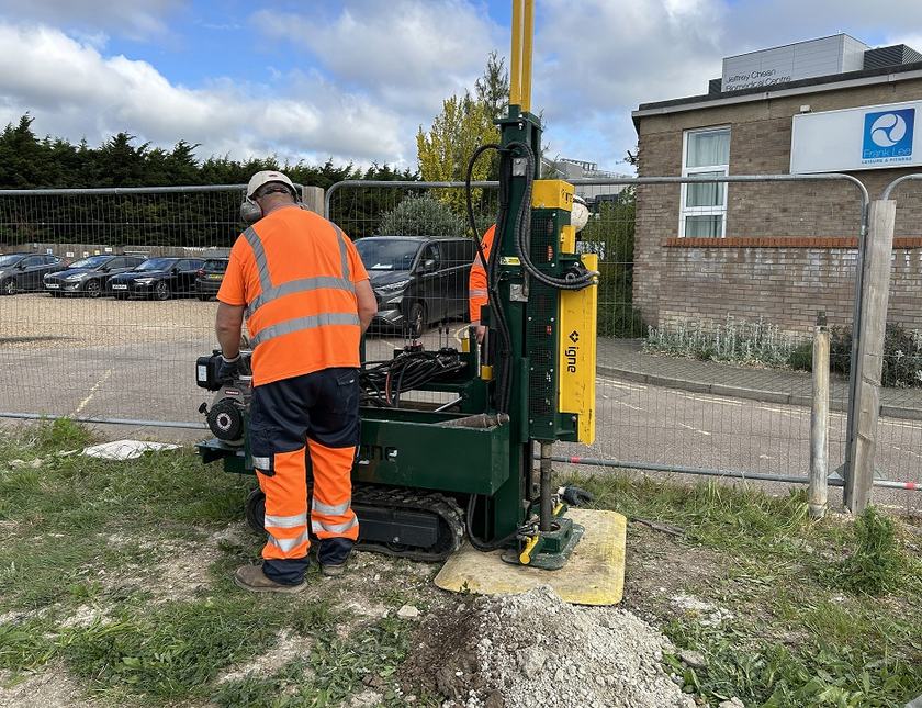 A construction worker wearing a high-vis jacket outside a building using a large machine on the ground