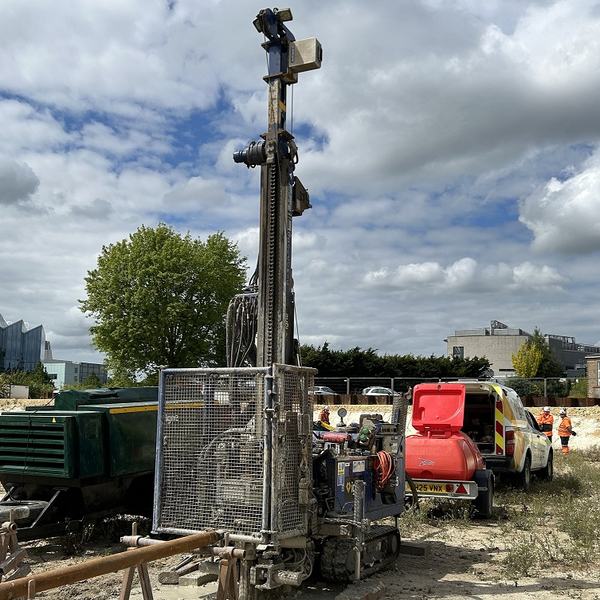 People working on a construction site with a large drill
