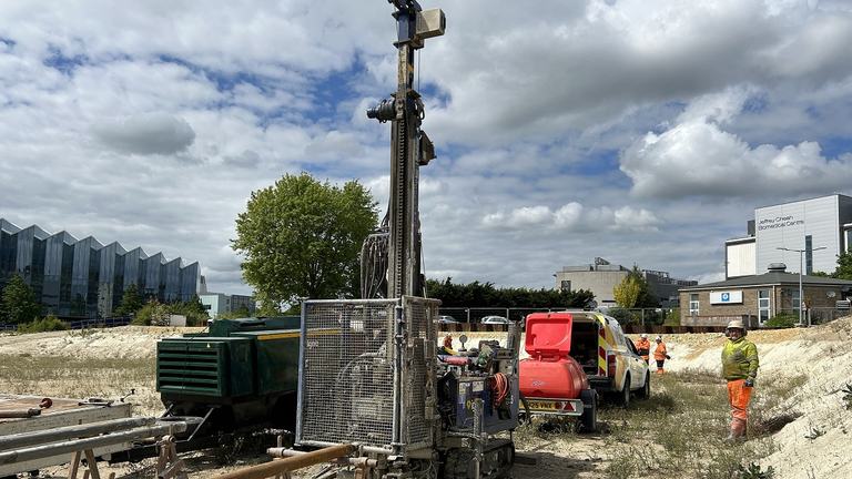 People working on a construction site with a large drill