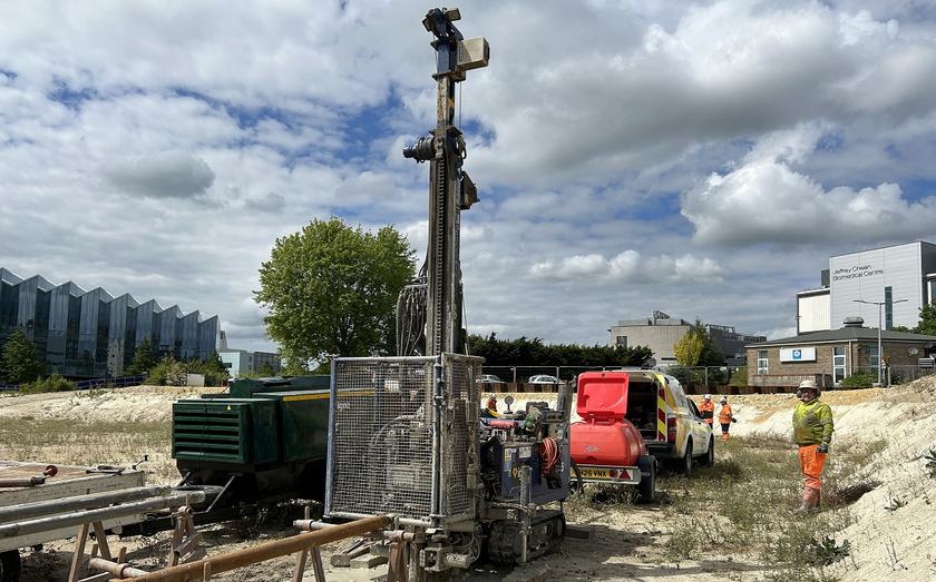 People working on a construction site with a large drill