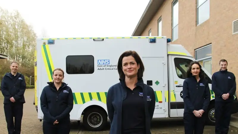 Adult critical care ambulance and crew members standing in front of it
