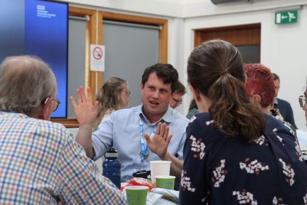 A group of clinical staff and patients talking to each other on a table