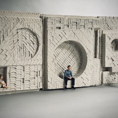 A clay model of a sculpture, with a child and adult sitting within the sculpture