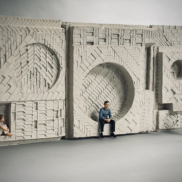 A clay model of a sculpture, with a child and adult sitting within the sculpture