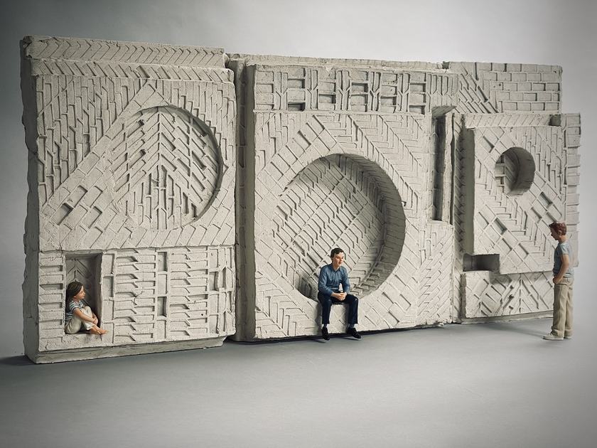 A clay model of a sculpture, with a child and adult sitting within the sculpture