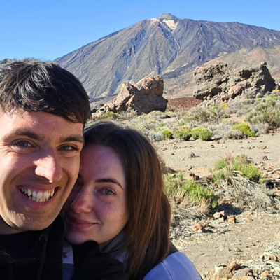 A selfie of Jack and Chloe in front of a volcanic landscape and blue sky
