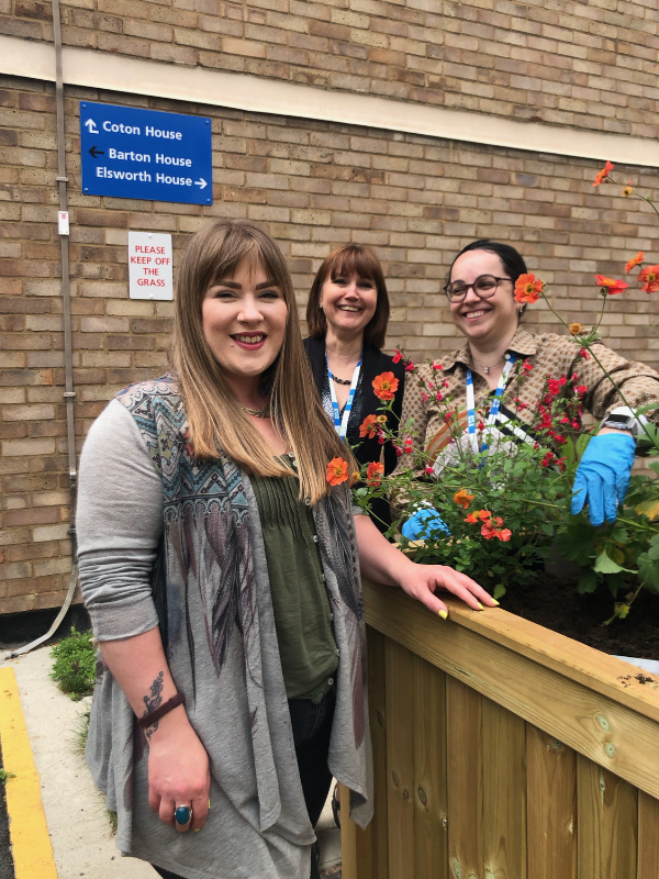 Jen Bailey with two colleagues from cleft services standing near planter filled with flowers