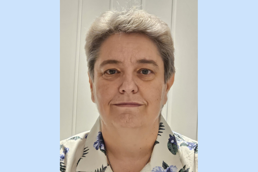 A headshot of a woman with short grey hair and a patterned blouse