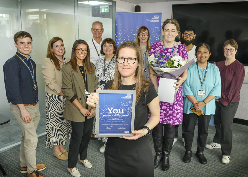 Kat Hymers with standing with a certificate. surrounded by her colleagues