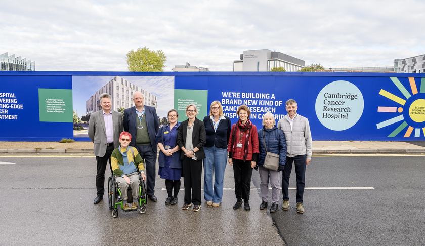 Patients and staff involved in the Cambridge Cancer Research Hospital programme are pictured standing in front of the the newly designed site hoardings. The hoardings are bright and an artist impression of the future hospital can be seen on them