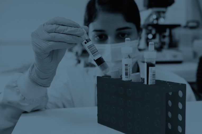 Woman in a lab taking a lab tube out of the small rack