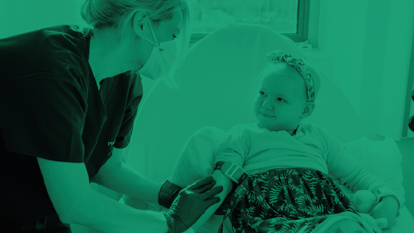 Nurse with a mask on with a child patient smiling at her