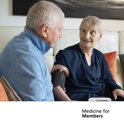 Two elderly people. One is having their blood pressure tested.