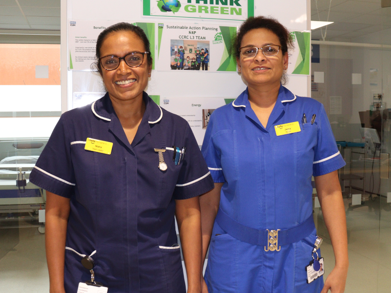 Two nurses standing inside in front of a green champion display